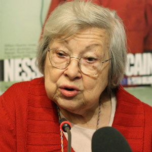 Lidia Menapace at a microphone at a press conference.