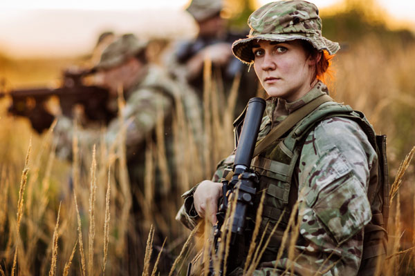 Photo of a woman in combat fatigues carrying an automatic weapon