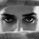 black and white close up of a woman's eyes as she looks through her cupped hands