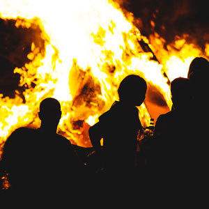 Silhouettes against a large bonfire